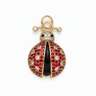 Decorative pendant with red stones, black center, and gold accents on a light purple background