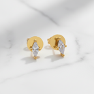 Gold earrings with clear gemstones on a light gray background