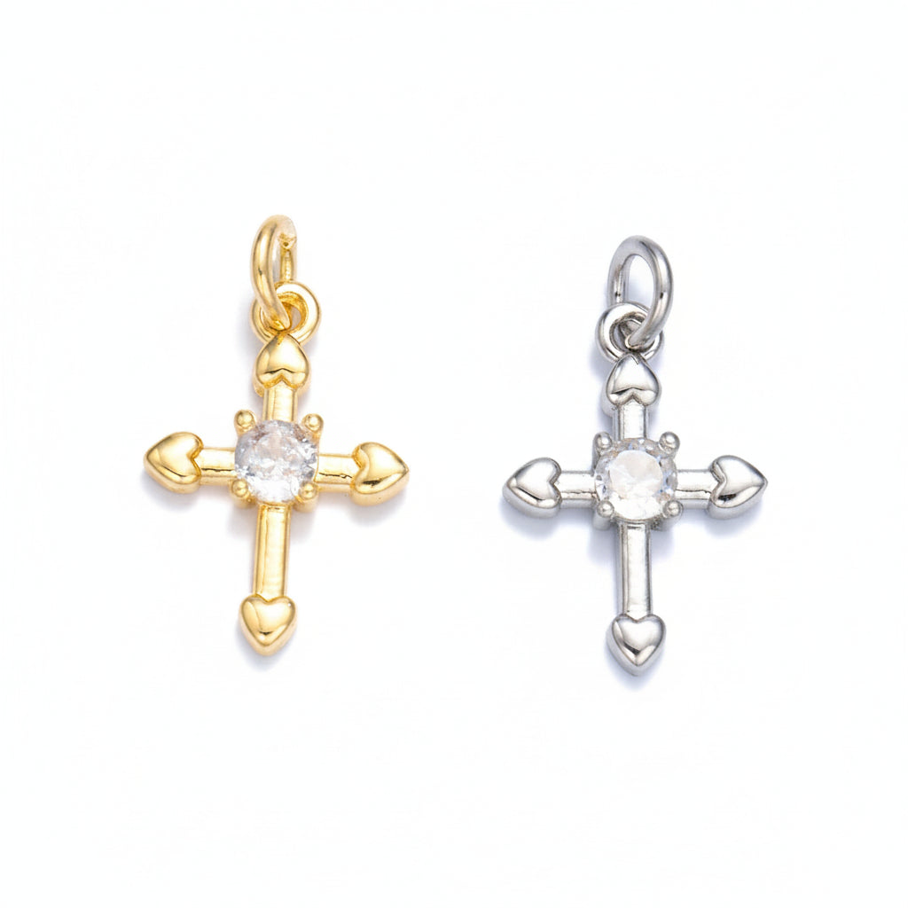 Gold and silver cross-shaped pendants with heart details on a light gray background