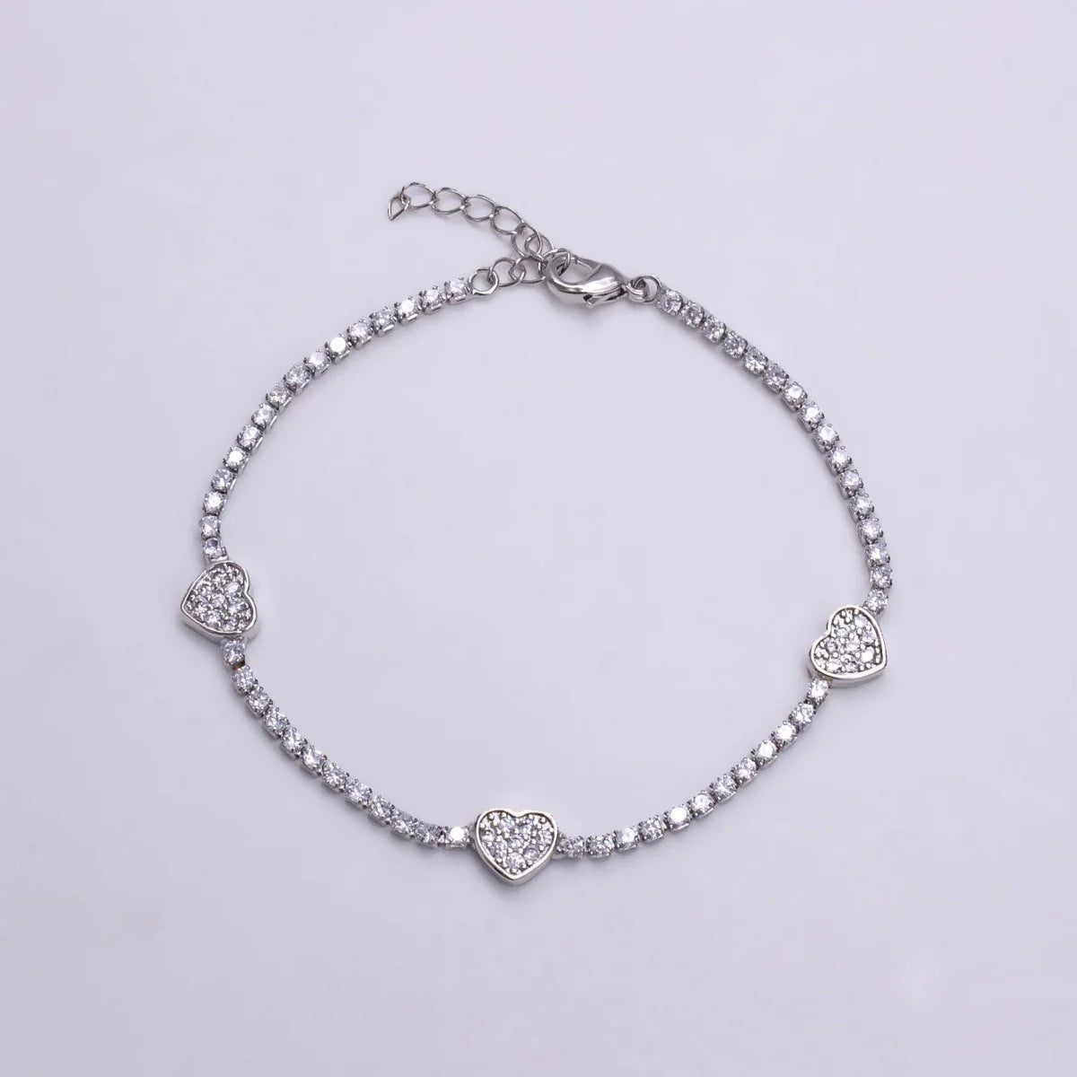 Silver bracelet with heart-shaped charms on a light gray background