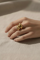 Gold ring on a hand against a beige background