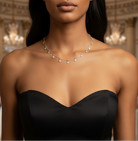 Woman wearing a black strapless dress and silver necklace in an elegant indoor setting.