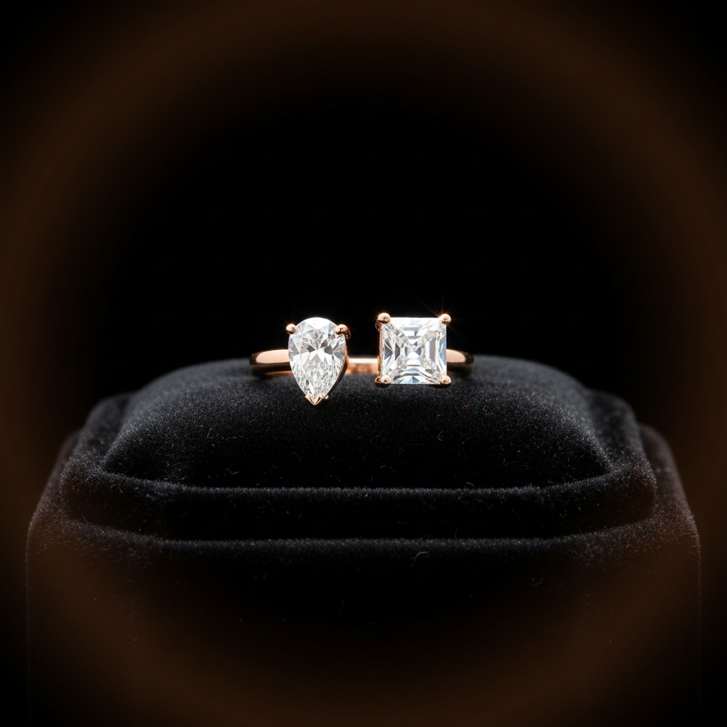 Two diamond earrings on a black velvet cushion with a dark background