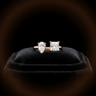 Two diamond earrings on a black velvet cushion with a dark background