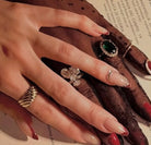 Close-up of a hand wearing multiple rings with a brown fabric background