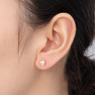 Gold earring worn on a person's ear with a neutral background