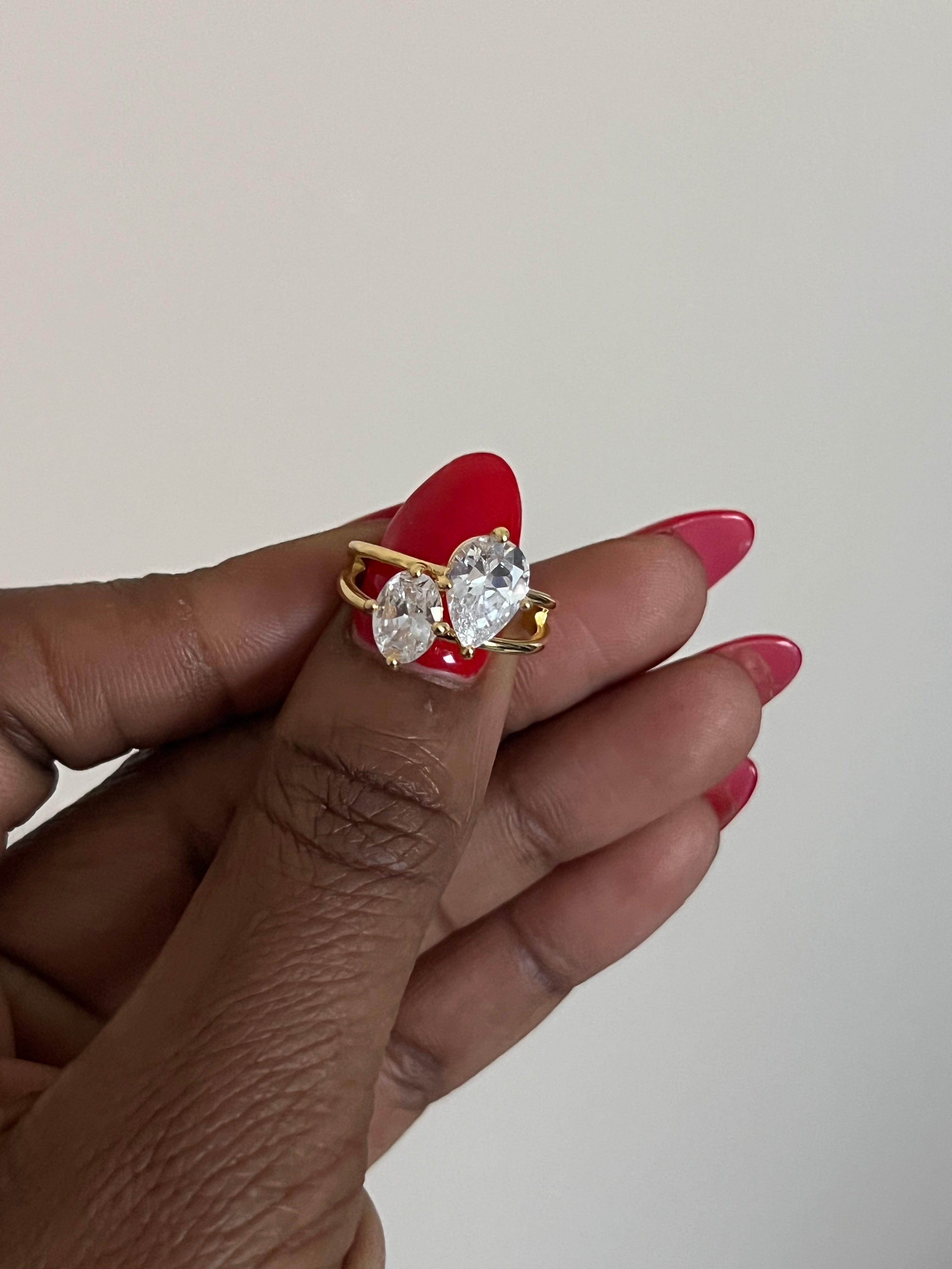 Hand holding a diamond ring with a red stone against a plain background