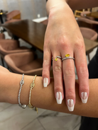 Close-up of a hand with two rings and a bracelet in an indoor setting