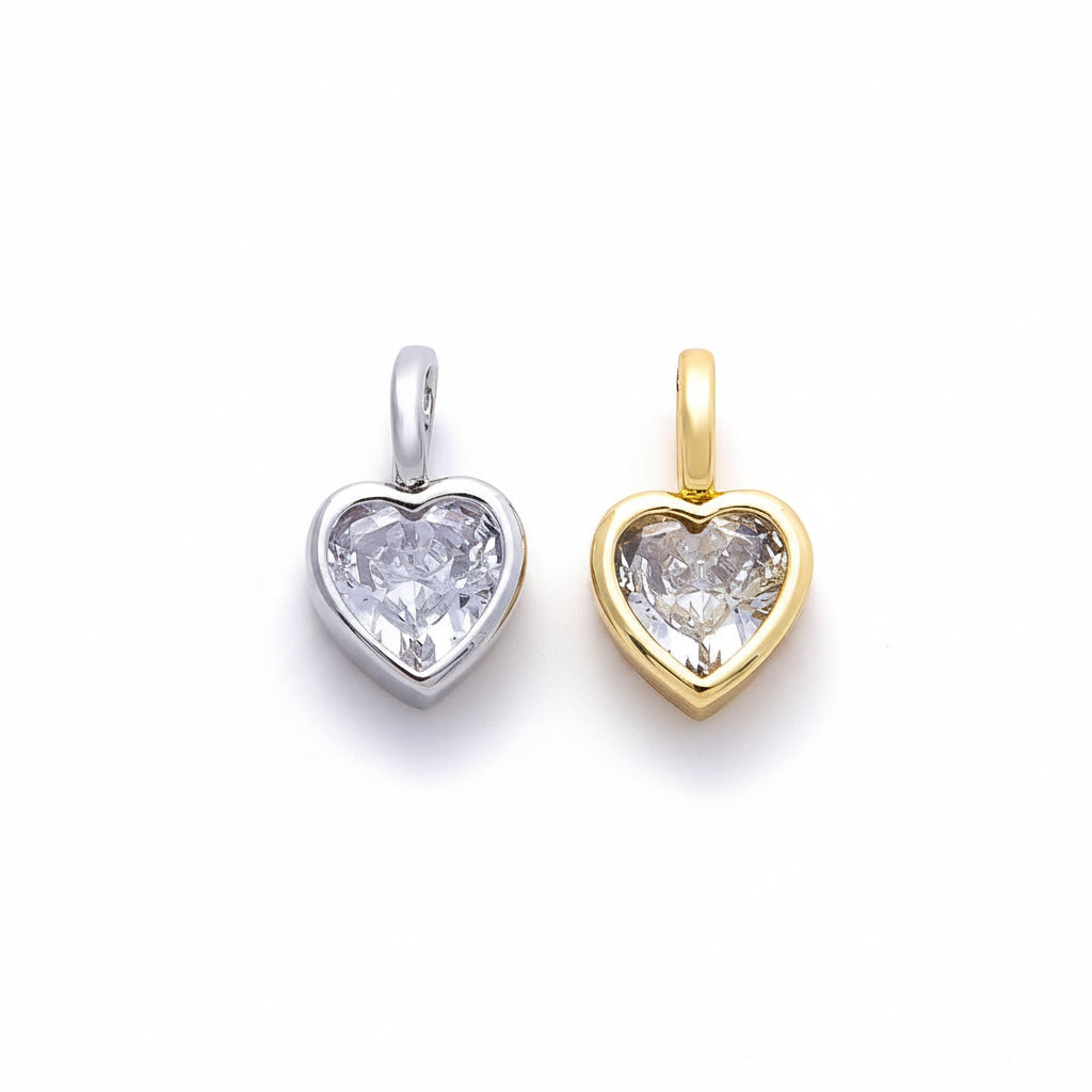 Two heart-shaped crystal pendants, one in silver-tone metal and one in gold-tone metal, displayed side-by-side on a clean white background.