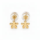 Gold flower-shaped earrings on a light purple background