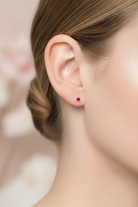 Close-up of a person wearing a red earring with a blurred background