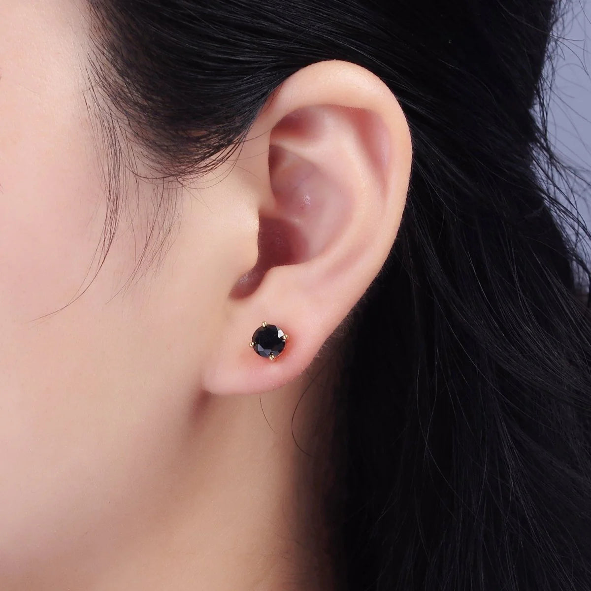 Close-up of an ear wearing a black stud earring with blurred background