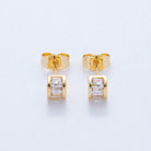 Gold earrings with clear gemstones on a light gray background