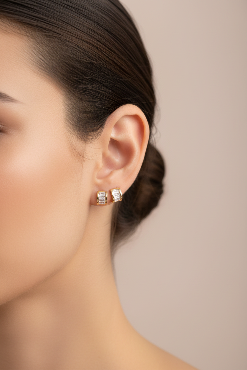 Close-up of a woman wearing diamond stud earrings against a neutral background