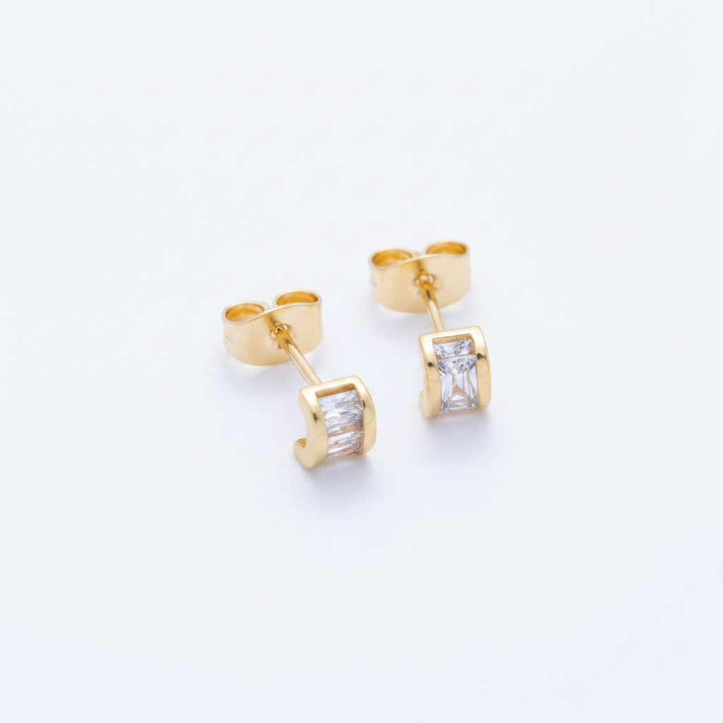 Gold stud earrings with clear gemstones on a light gray background