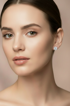 Close-up of a woman wearing a diamond earring against a neutral background