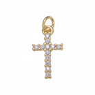 A gold cross pendant adorned with small clear gemstones, set against a plain light gray background.