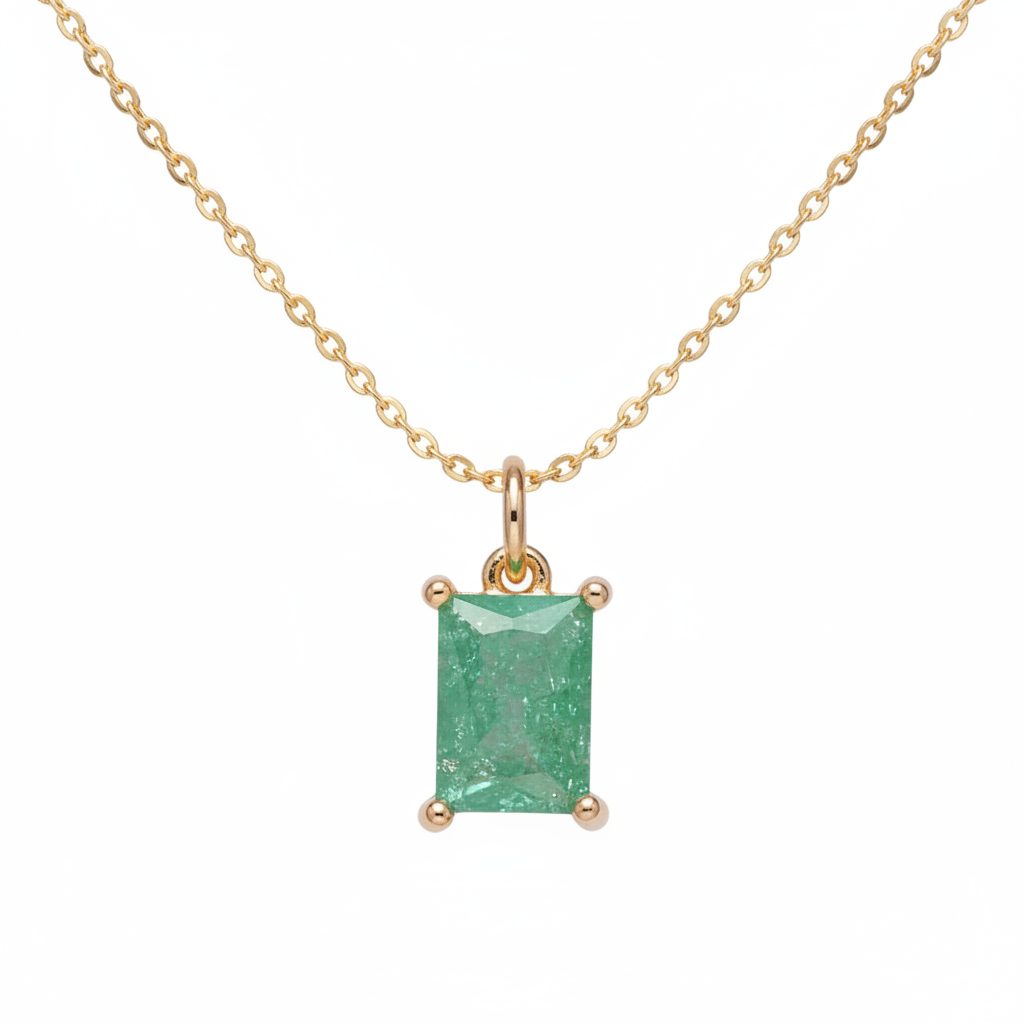Green gemstone pendant with gold setting on a light purple background