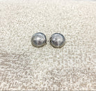 Pair of silver shell-shaped earrings on a textured beige surface
