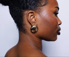 Profile of a woman wearing a gold earring against a light background