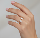 Hand wearing two diamond rings on a neutral background