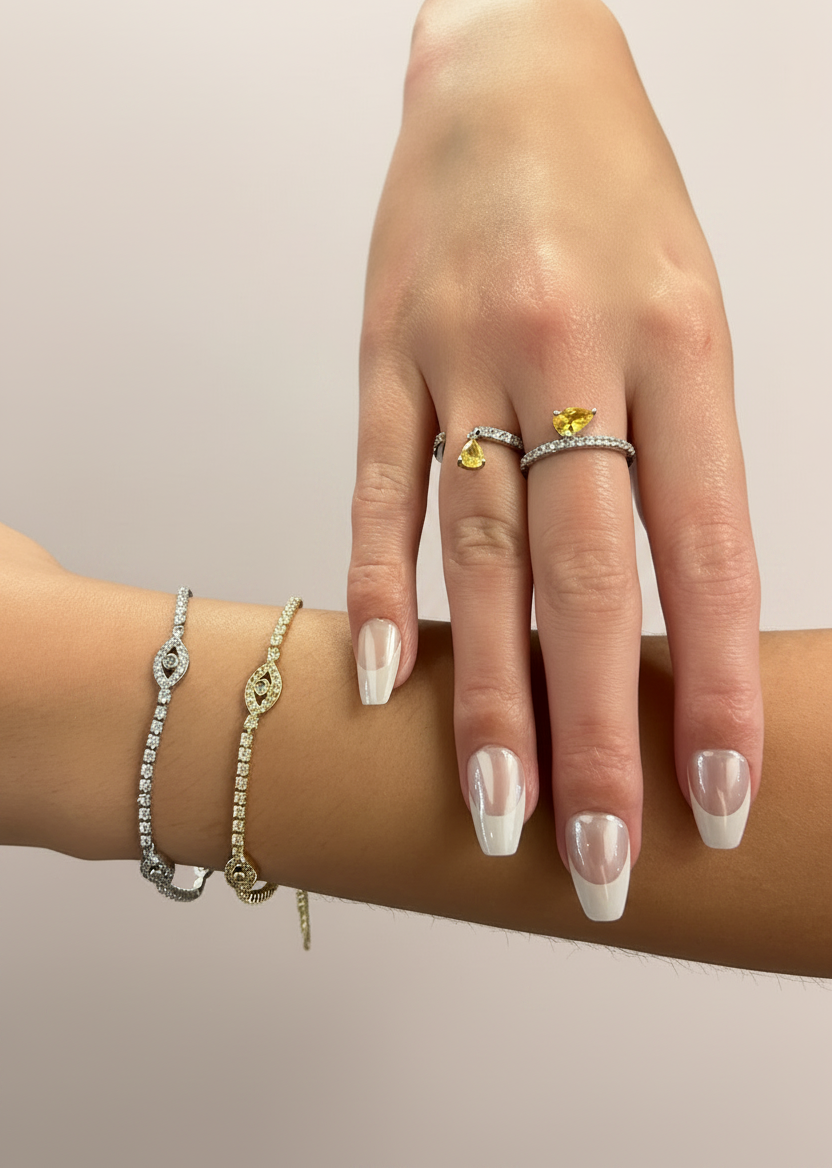 Hand wearing multiple rings and bracelets on a neutral background
